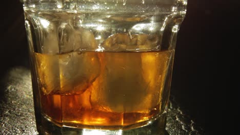 Glas-Mit-Eiswürfeln-Gefüllt-Mit-Schnaps-Oder-Whiskey-Farbe-Bernstein-Von-Hinten-Beleuchtet