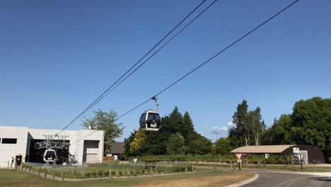 Two-Skyline-gondola-glide-past-each-other-along-the-cables-under-a-clear-blue-sky-in-Rotorua-New-Zealand