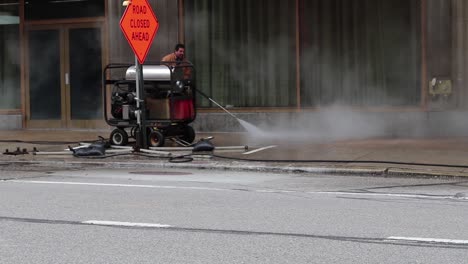 A-city-worker-sprays-sanitizer-up-and-down-a-public-sidewalk-to-clean-the-effects-from-covid-19,-coronavirus