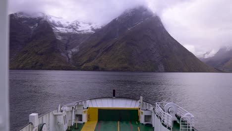 Slow-motion-shot-of-large-ferry,-surrounded-by-ocean-and-beautiful-foggy-mountain-peak-scenery-in-front-of-the-boat