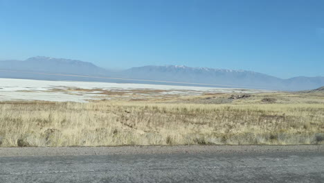 Driving-by-the-shores-of-the-salt-lake-and-fields-of-dry-grass-in-Antelope-Island-Utah