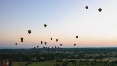 Aerial-slide-left-of-hot-air-balloons-flying-over-Bagan,-Myanmar-at-sunrise