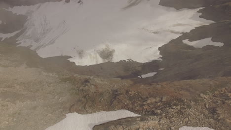 A-drone-flies-over-a-sheer-cliff-face-of-a-mountain-as-the-camera-tilts-downward-into-the-depths-below