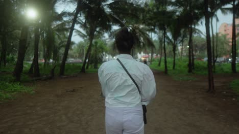 Person-walking-through-a-palm-tree-forest-during-twilight